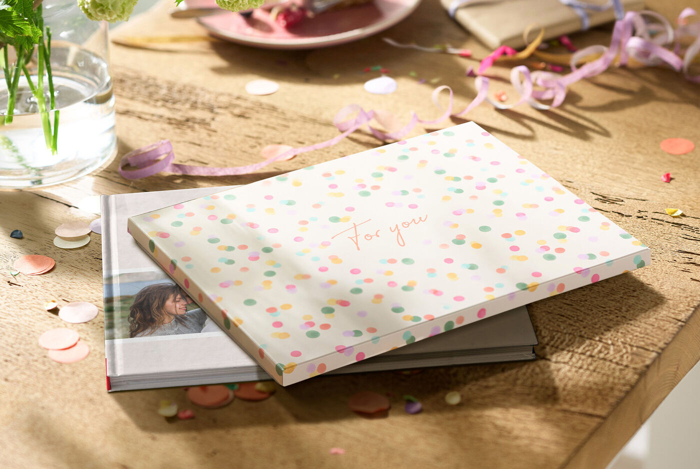 CEWE FOTOBUCH Geschenkverpackung mit bunten Punkten liegt auf einem Tisch.