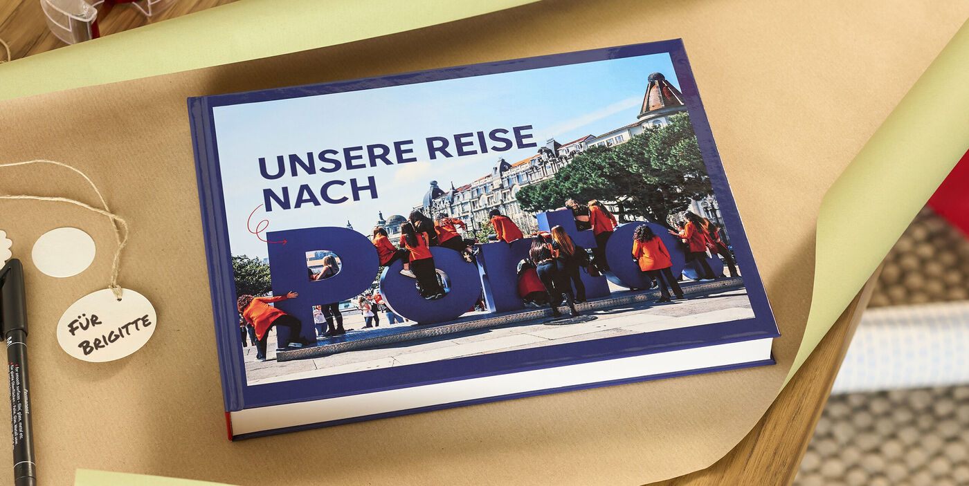 Geschlossenes CEWE FOTOBUCH mit dem Titel "Unsere Reise nach Porto" auf Geschenkpapier