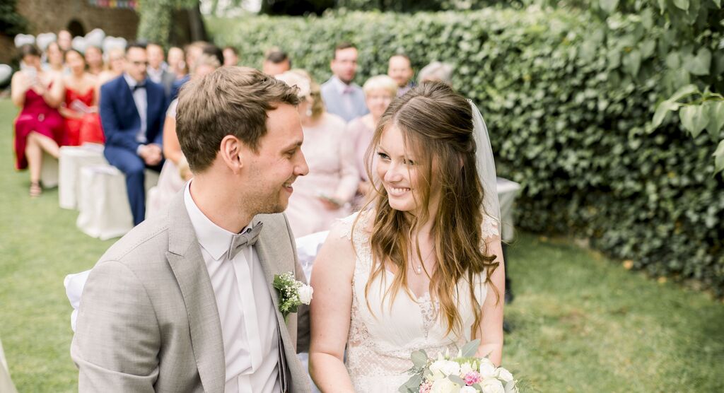 Ein glückliches Paar während ihrer Hochzeit im Freien, umgeben von Gästen