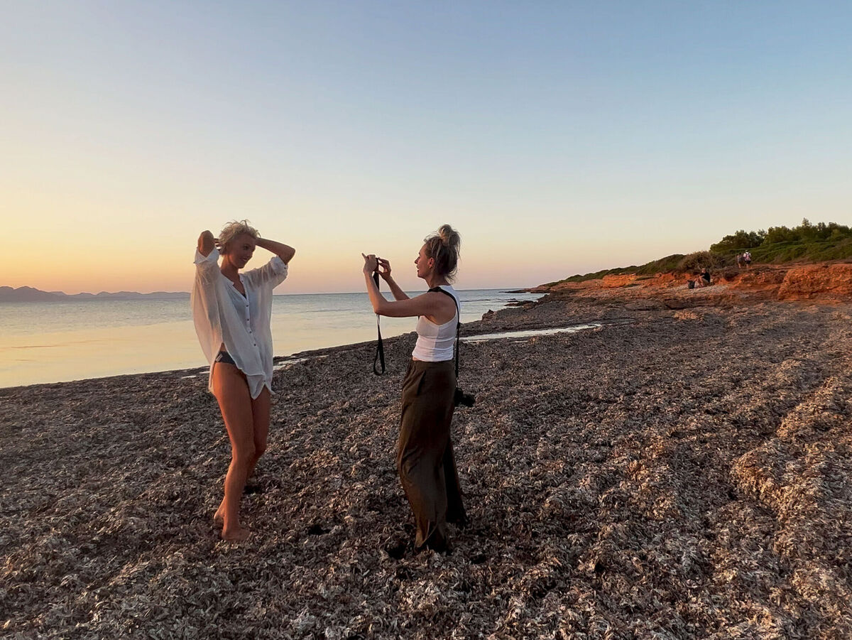 Zwei Frauen am Strand genießen den Sonnenuntergang und machen Fotos