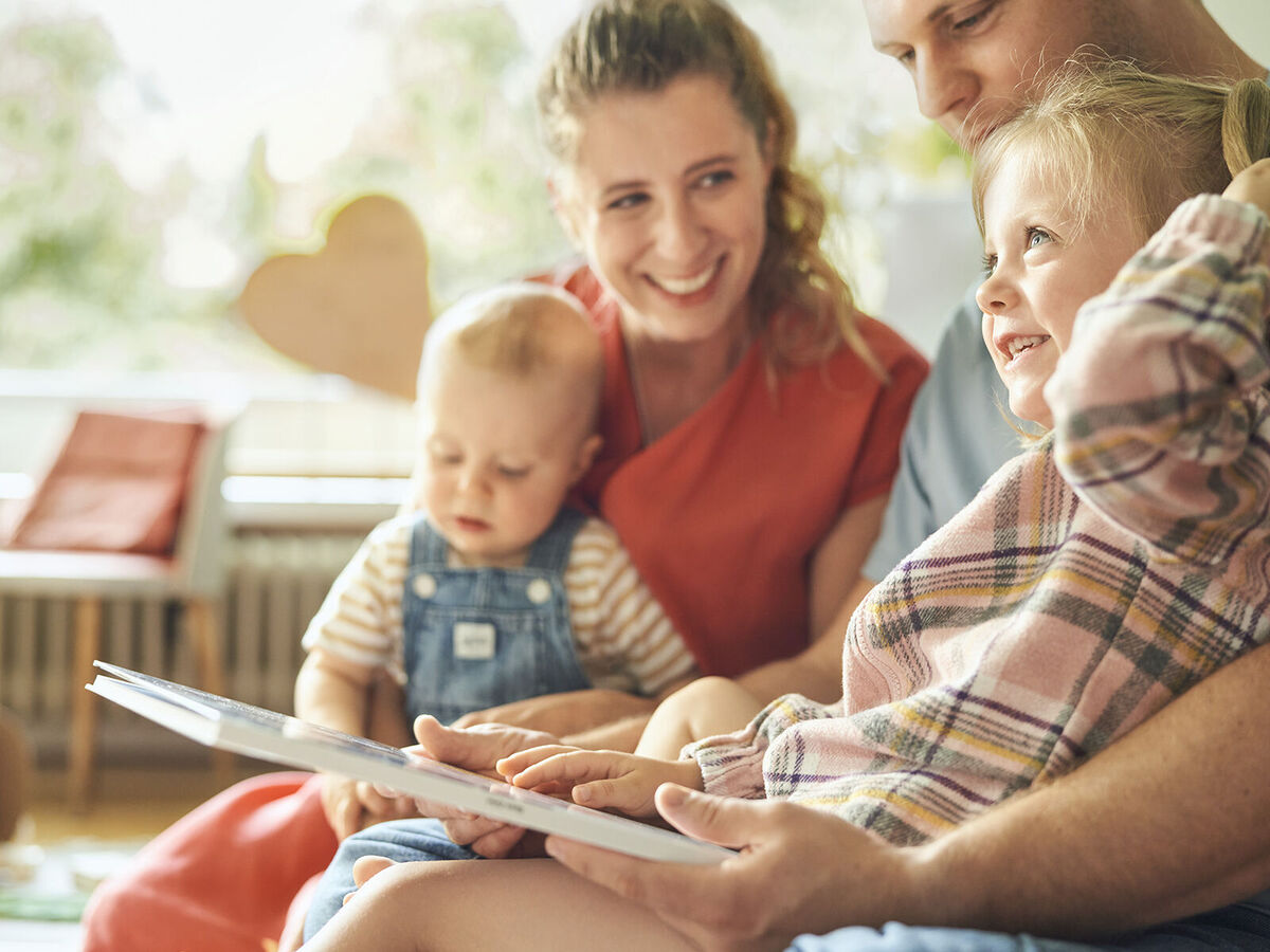 Eine Familie sitzt zusammen, während sie einem Kind ein Buch vorliest, umgeben von einer warmen Atmosphäre