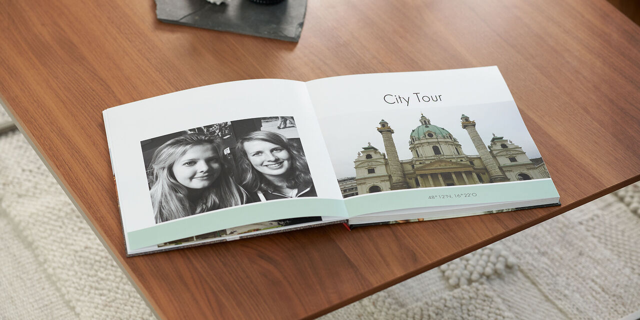 Zwei Freundinnen blättern in einem Fotobuch mit Erinnerungen an die Städtereise.