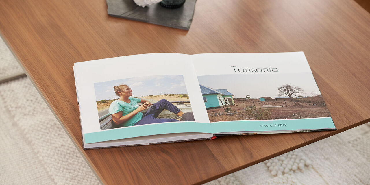 Eine geöffnete CEWE FOTOBUCH zeigt Bilder aus Tansania. Neben einer Person, die entspannt sitzt.