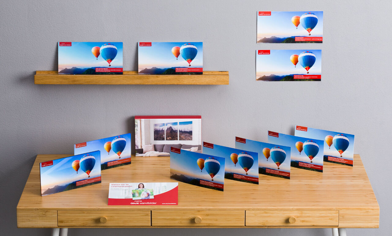 Bunte Grußkarten mit Ballons auf einem Tisch und an der Wand. CEWE Grußkarten