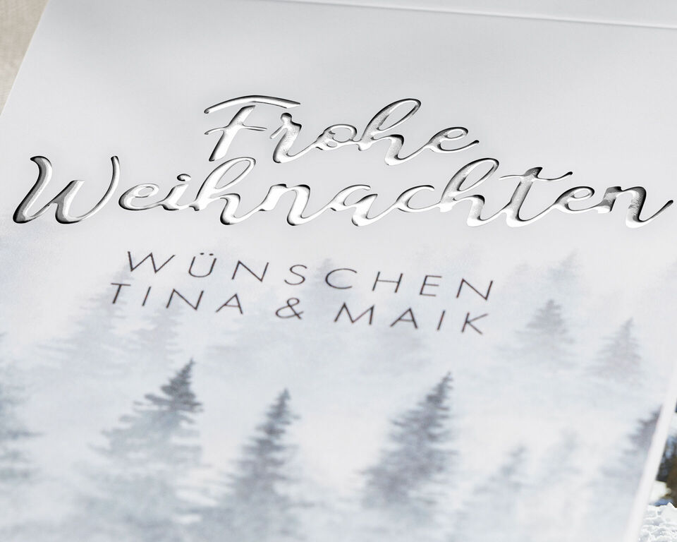 Weihnachtskarte mit der Aufschrift 'Frohe Weihnachten' und einem winterlichen Wald im Hintergrund