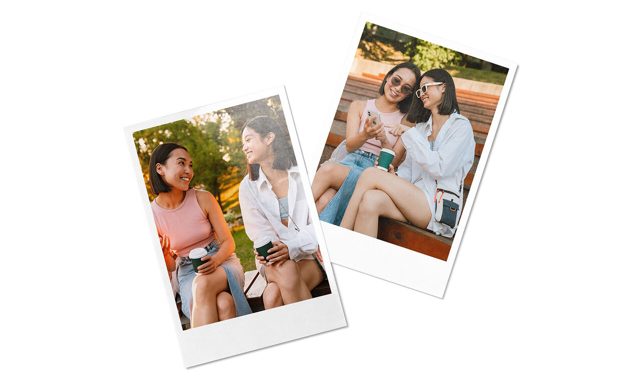 Zwei Frauen sitzen im Park und unterhalten sich. Eine hält einen Kaffeebecher in der Hand.