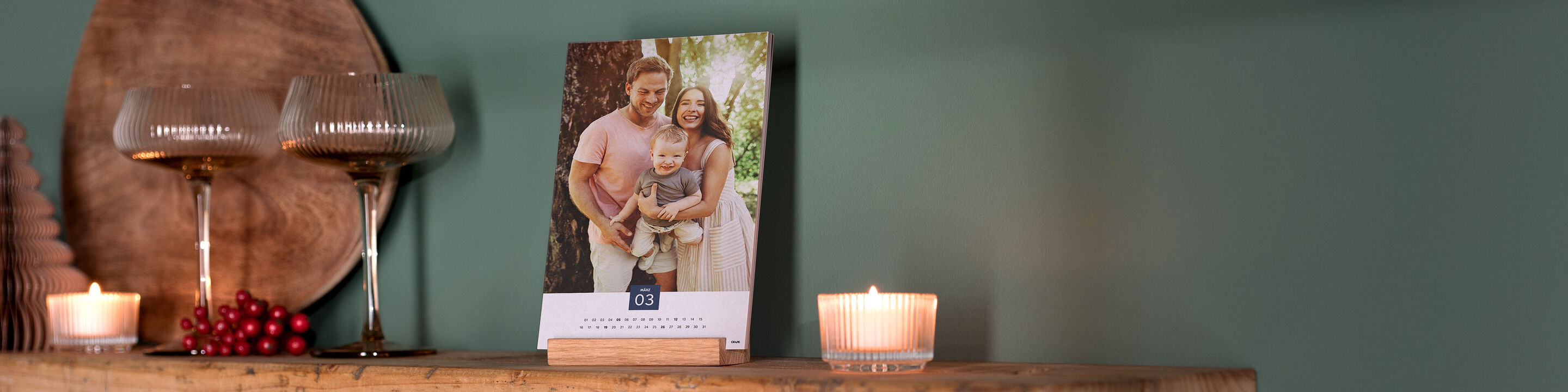 Ein wunderschöner CEWE Fotokalender mit einem Familienmotiv auf einem Tisch neben Kerzen und Deko.
