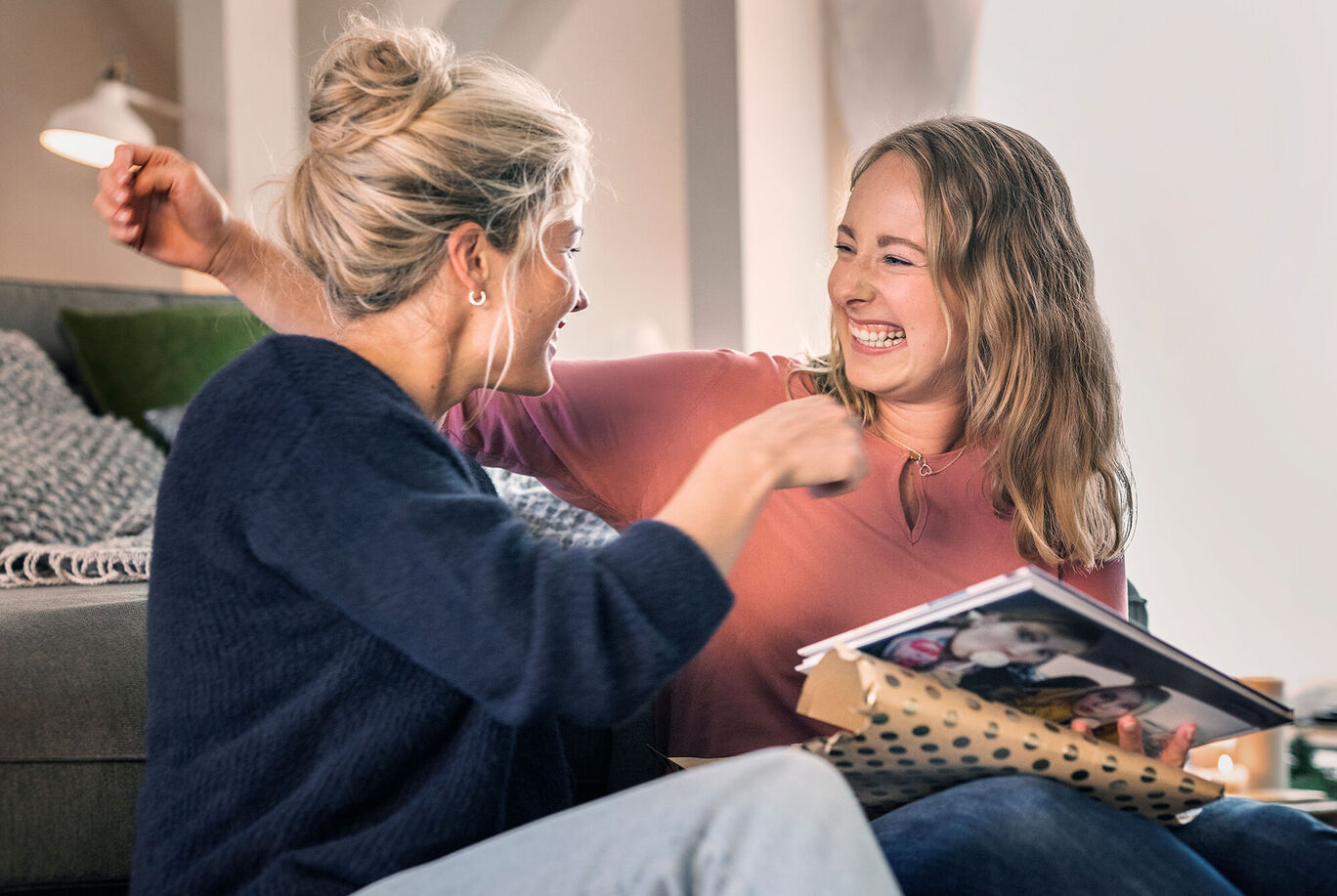 Zwei Frauen sehen sich ein Fotobuch an und teilen Erinnerungen.