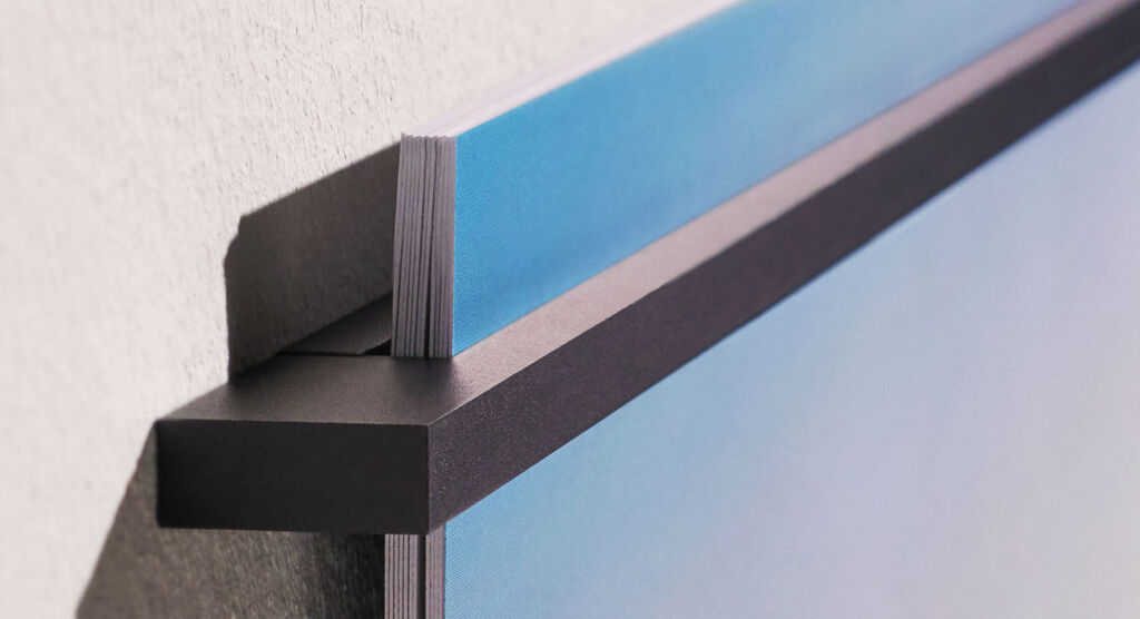 Nahaufnahme der schwarzen, magnetischen Metallleiste des Wandkalender Fineline, die an einer Wand befestigt ist und Kalenderblätter hält.