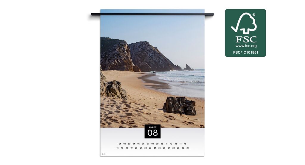 Strandlandschaft mit Felsen und sanften Wellen unter einem blauen Himmel, abgebildet in einem Wandkalender für den Monat August