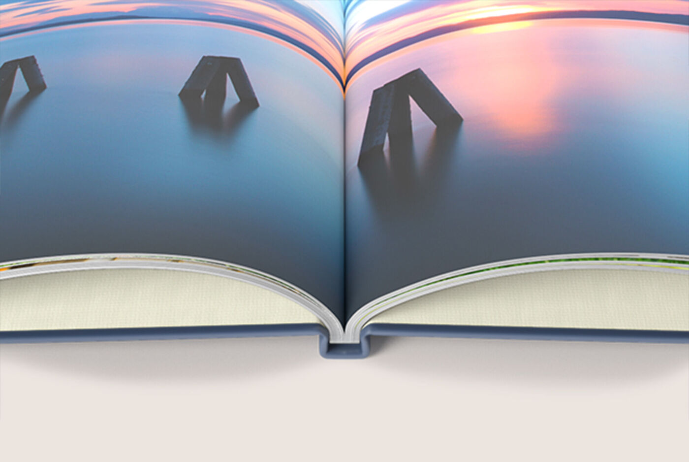 Offenes CEWE FOTOBUCH mit Bildern von ruhiger Landschaft und Statuen, sanfte Farben reflektieren im Wasser