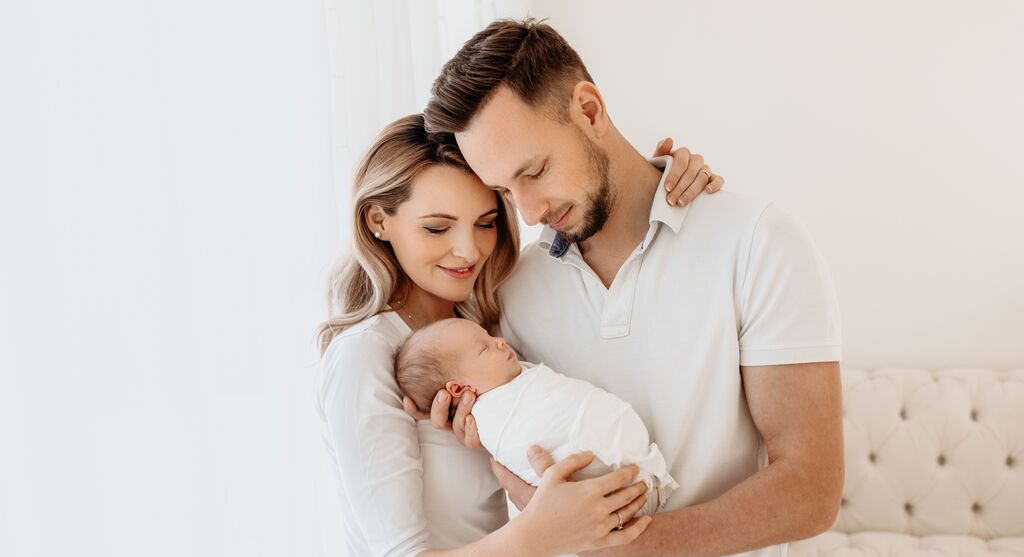 Ein liebevolles Paar hält ein Baby in den Händen. Sie strahlen Freude und Zuneigung aus.