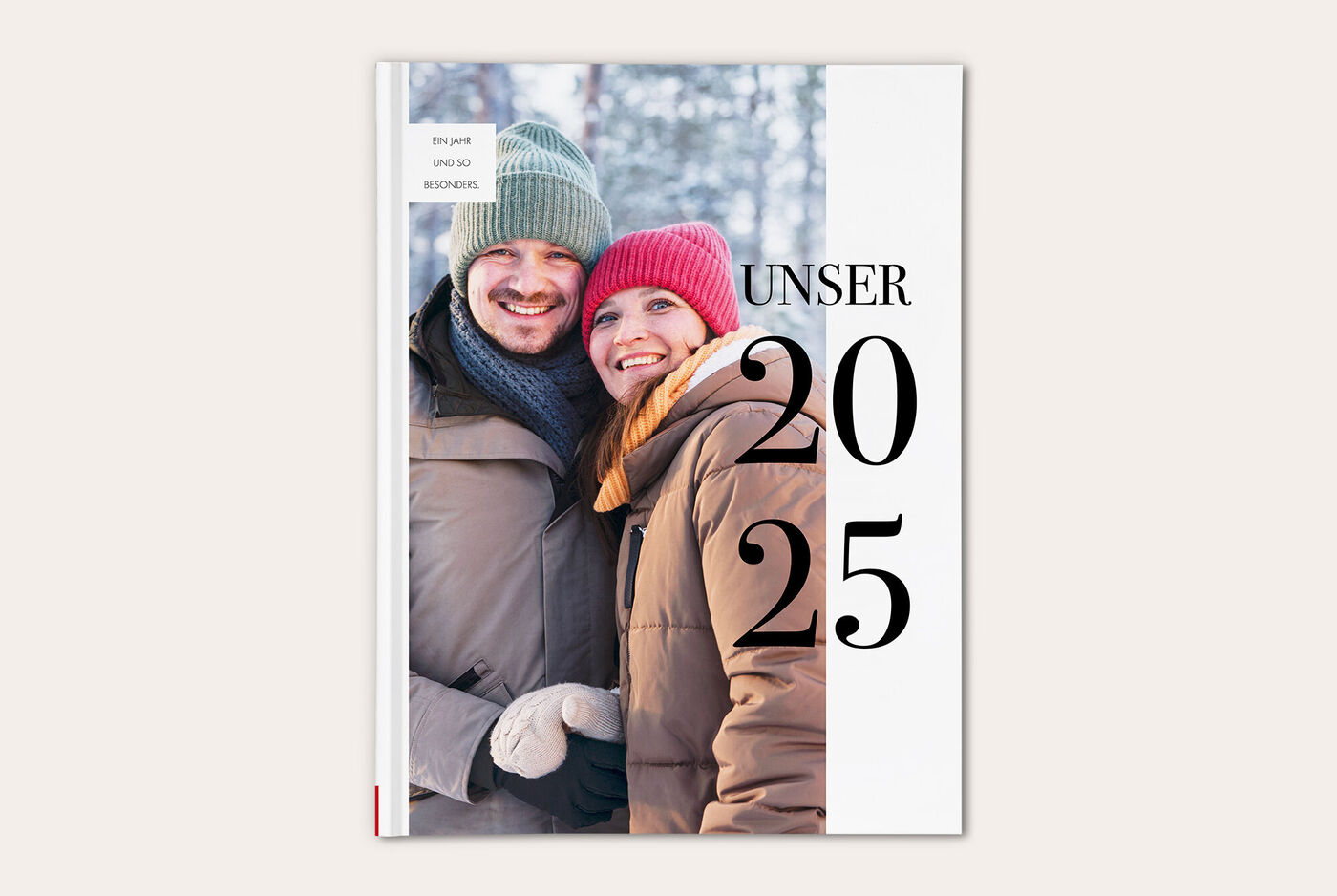 Zwei Personen in winterlicher Kleidung stehen in einer verschneiten Landschaft und lächeln. Sie tragen bunte Mützen.