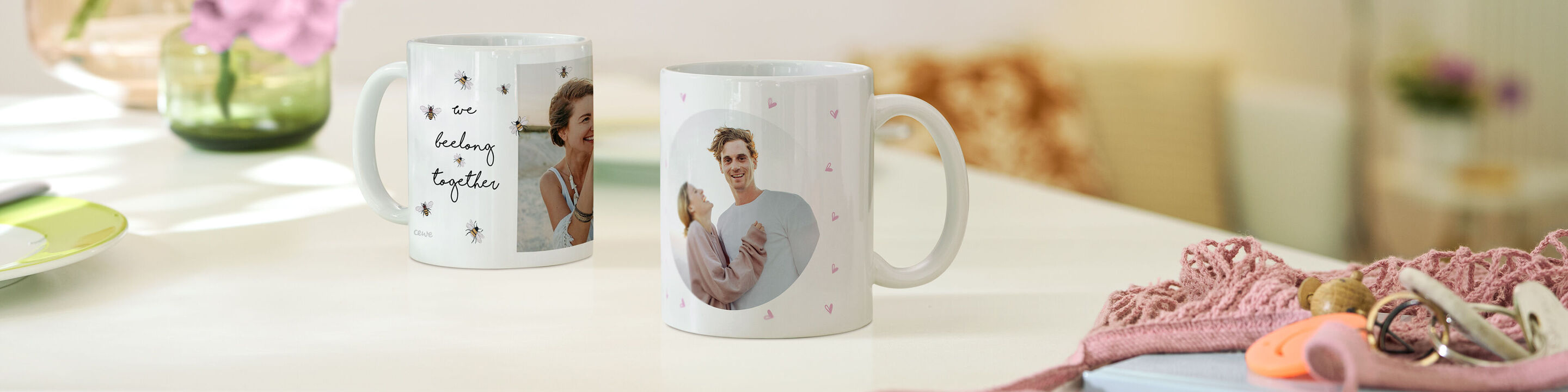 Zwei personalisierte Tassen auf einem Tisch. Eine Tasse zeigt ein fröhliches Porträt von Menschen und die andere hat ein kreatives Design.
