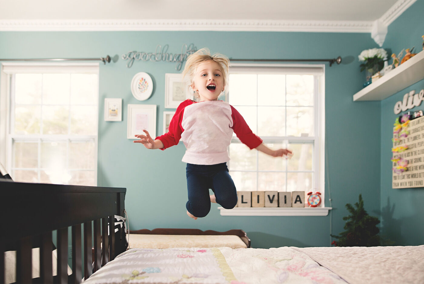 Ein kleiner Junge springt fröhlich auf einem Bett in einem hellen Kinderzimmer