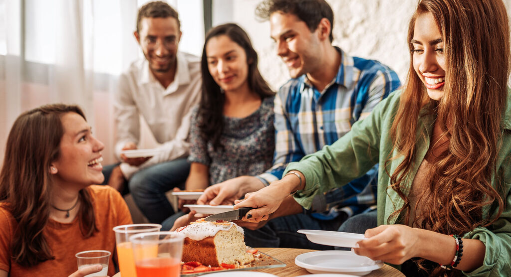 Menschen genießen ein gemeinsames Essen mit einem Kuchen auf einem Tisch