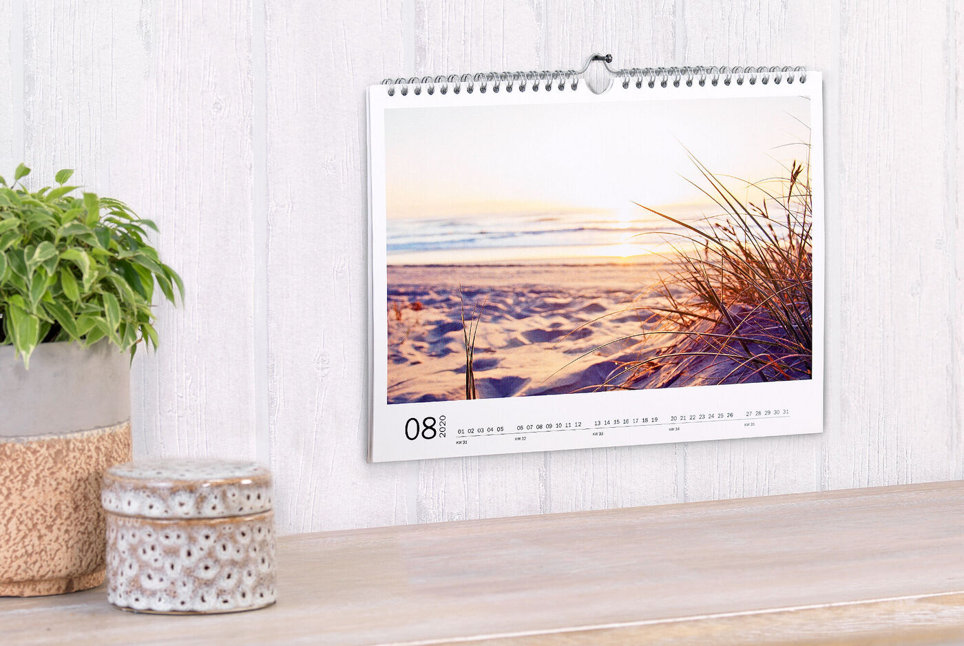 Ein schöner Kalender mit einem Sonnenuntergang am Strand und sanften Gräsern im Vordergrund