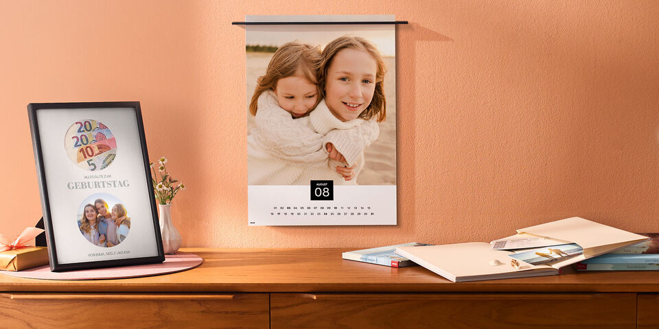 Zwei Personen zeigen einen bunten Fotokalender im Wohnzimmer