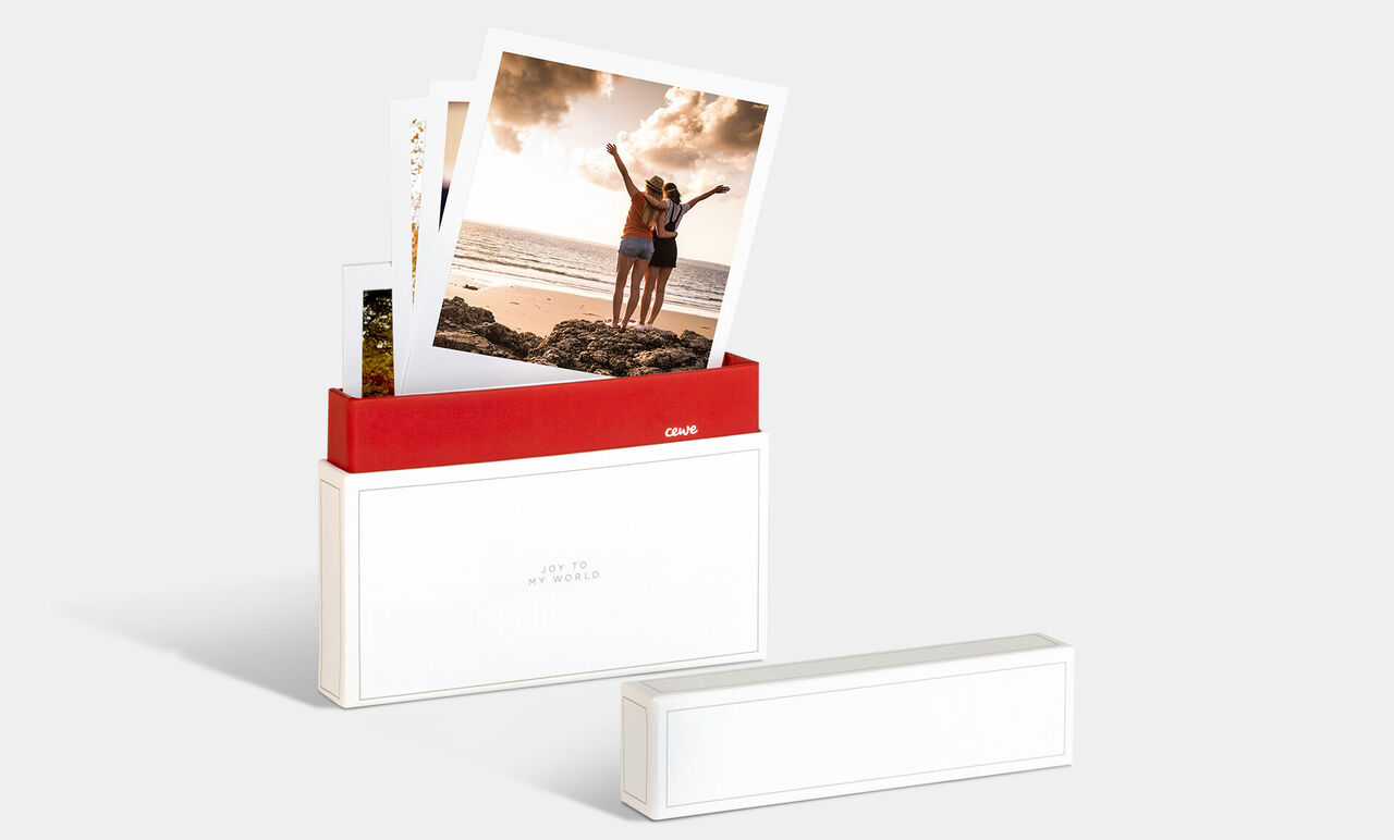 Eine CEWE Fotobox mit Fotos von zwei fröhlichen Personen am Strand.