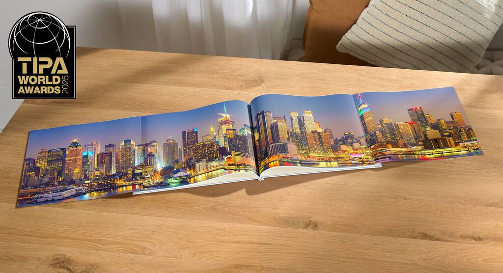 CEWE Fotobuch mit beeindruckendem Skyline-Bild einer Stadt bei Nacht auf einem Tisch