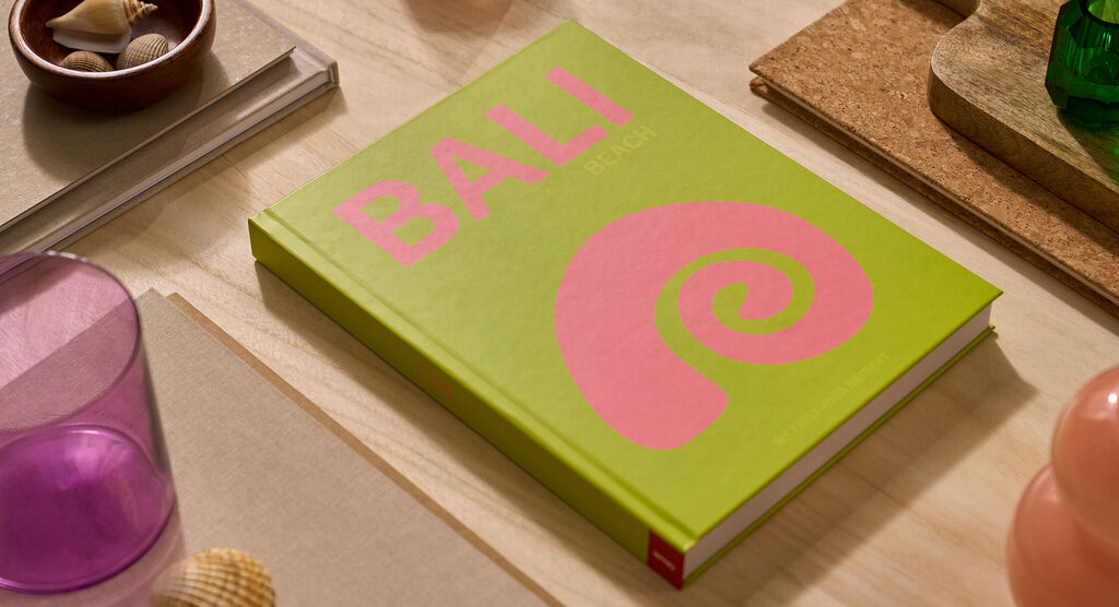 Auf einem Tisch liegt ein CEWE FOTOBUCH. Das Cover ist hellgrün und mit dem Schriftzug „Bali“ gestaltet.