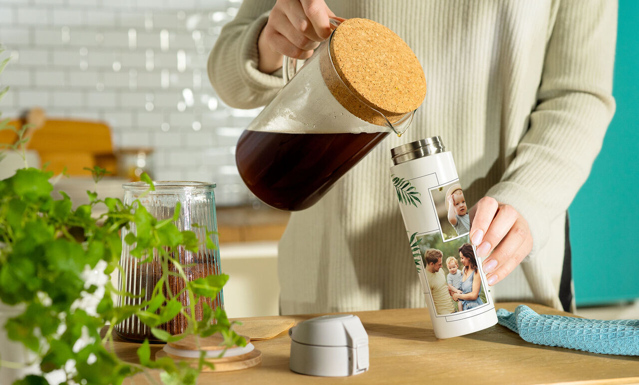Eine Person gießt Kaffee aus einer Kanne in eine personalisierte Thermosflasche mit Fotos.
