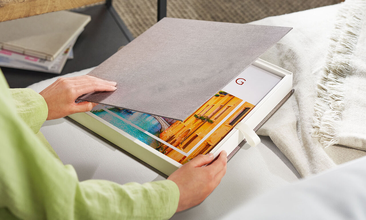 Person öffnet Geschenkbox mit CEWE FOTOBUCH Venedig