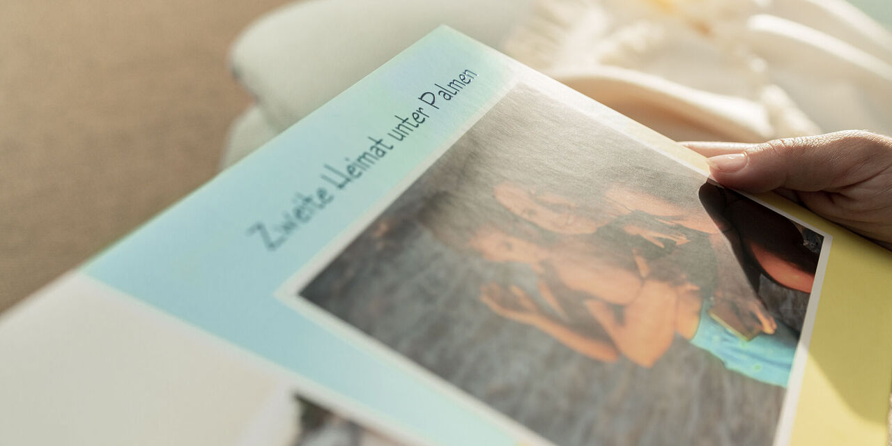 Eine Person hält ein CEWE Fotobuch mit einem Familienfoto auf der Vorderseite.