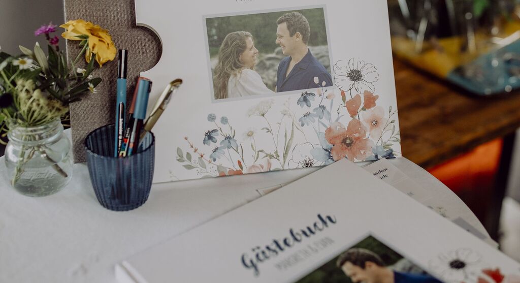 Ein liebevoll gestaltetes Gästebuch mit floralen Motiven und Fotos, um besondere Erinnerungen festzuhalten