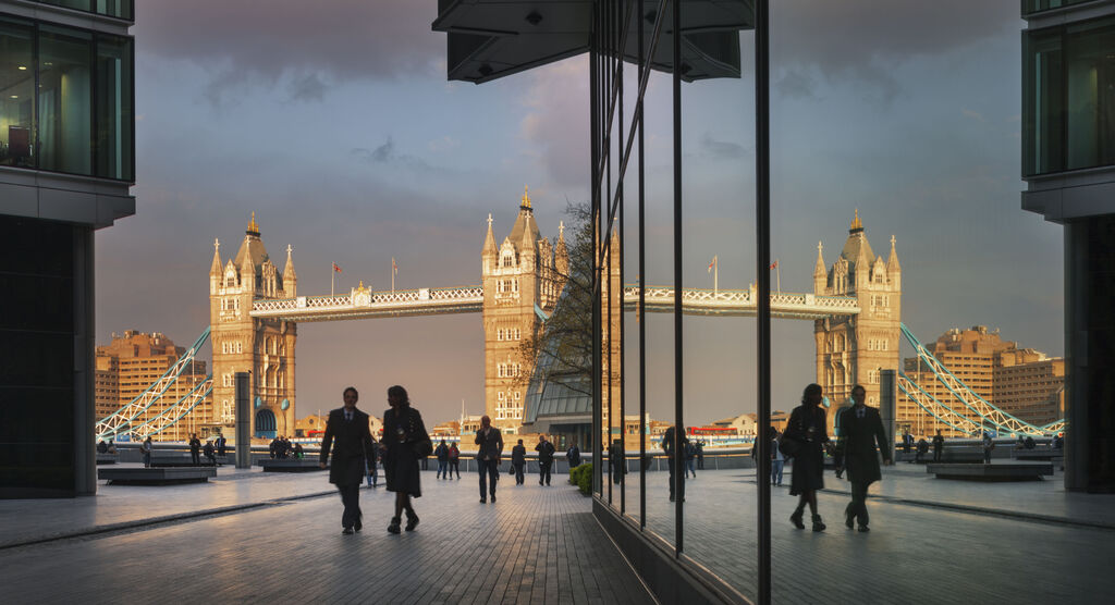 Spiegelnde Glasfassade in London mit Passanten und Architektur.