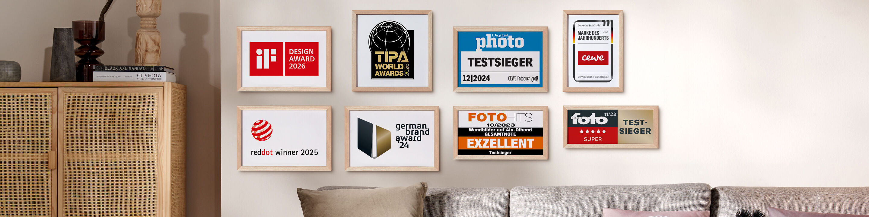 Mehrere gerahmte Auszeichnungen und Testsiegel hängen an einer Wand über einem Sofa und stehen für Qualität und Vertrauen