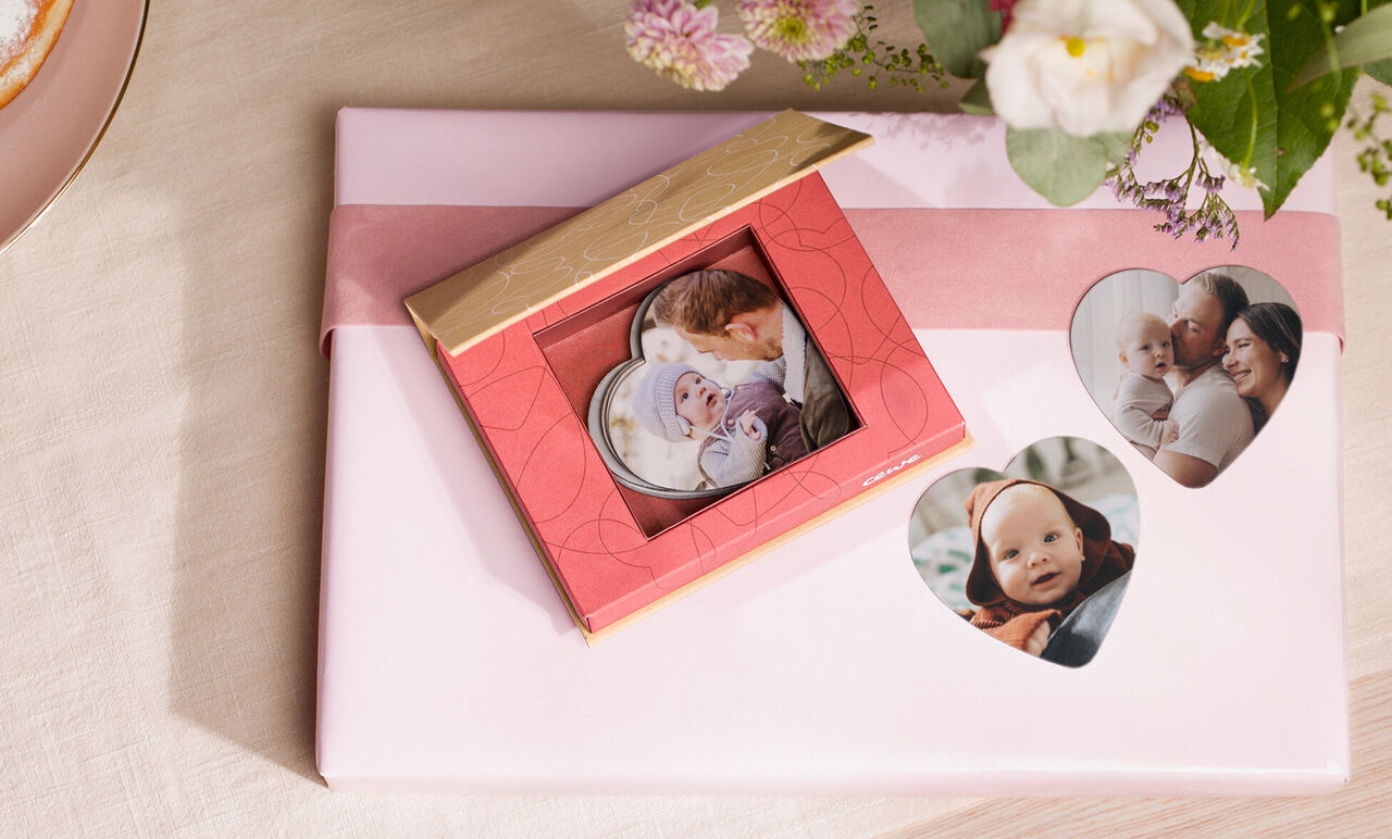 Ein schönes rotes Geschenk mit Fotokarten wird liebevoll präsentiert, umgeben von Blumen. Perfekt zum Verschenken von Erinnerungen.