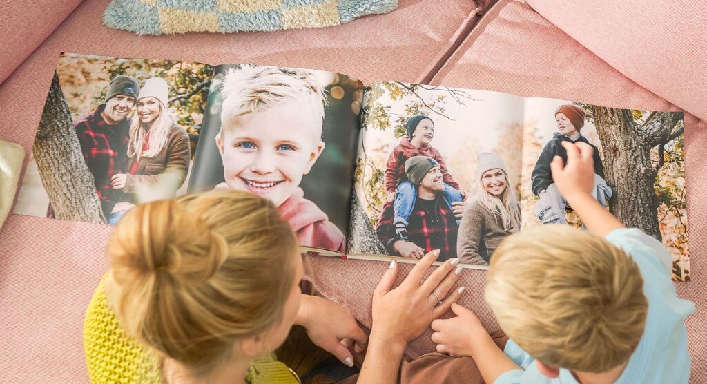 Eine Familie schaut gemeinsam in ein CEWE Fotobuch und genießt einen schönen Moment.
