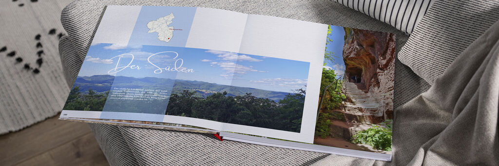 Ein offenes CEWE Fotobuch auf einem Tisch mit Bildern von der Süddeutschen Landschaft.