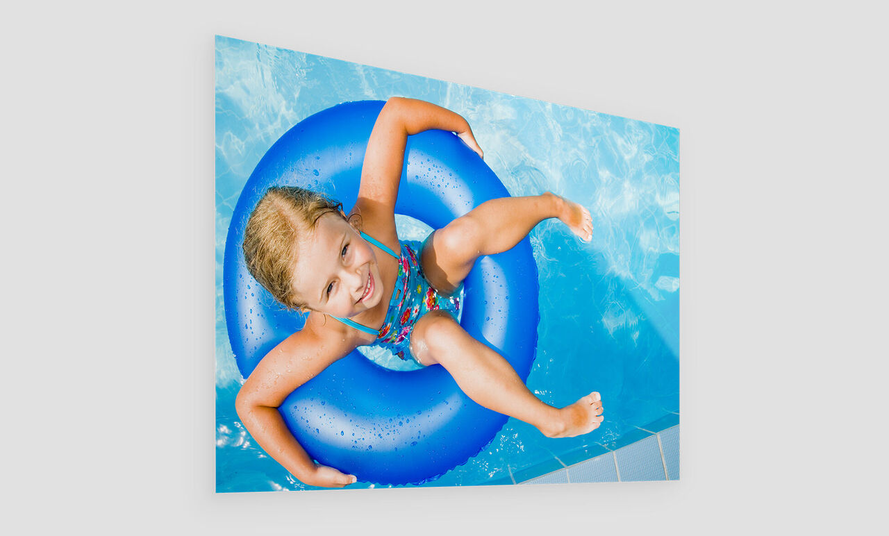 Ein Kind spielt fröhlich mit einem blauen Schwimmreifen im Wasser.