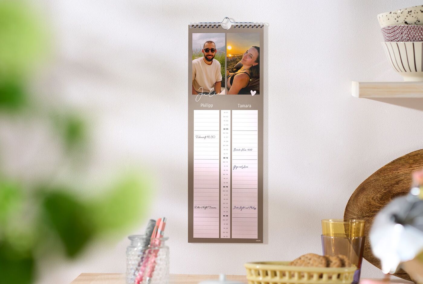 CEWE Fotokalender mit Gruppenfoto hängt an einer hellen Küchenwand