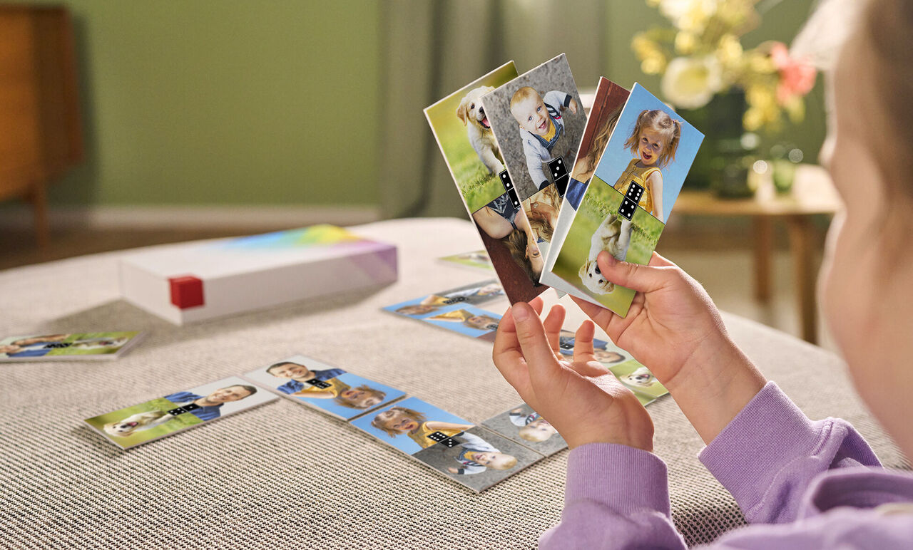 Ein Kind hält liebevoll Karten mit Familienfotos und bunten Motiven in den Händen