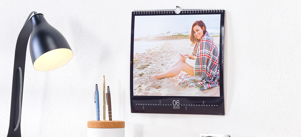 Ein stilvoller Fotokalender hängt an einer Wand. Der Juni zeigt eine entspannte Person am Strand. Sie genießt den Sonnenuntergang und die Atmosphäre.