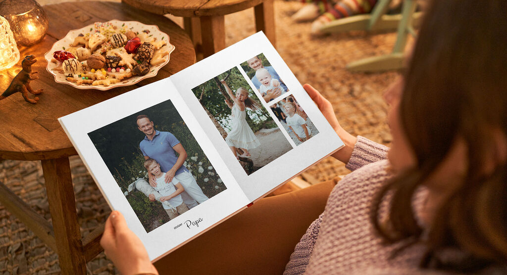 Eine Person blättert durch ein geöffnetes Fotobuch mit liebevollen Erinnerungen und Fotos.