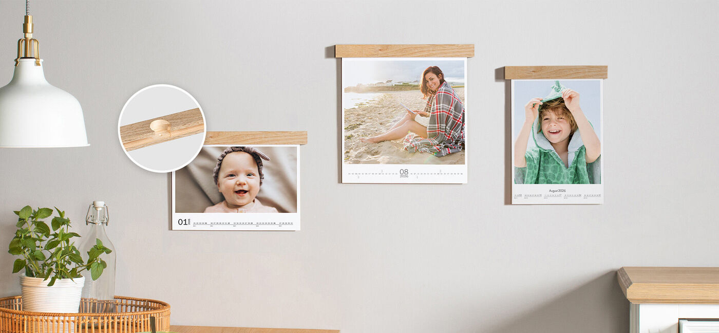 Drei CEWE Fotokalender an der Wand, aufgehängt mit einer Holzleiste.