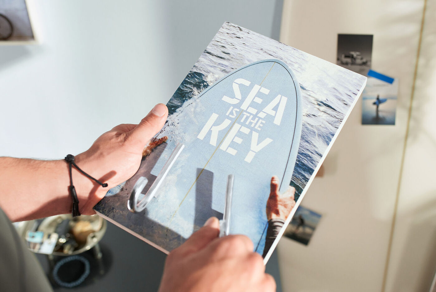 Ein Mann hält ein Fotobuch mit einem Surfbrett-Cover in der Hand.