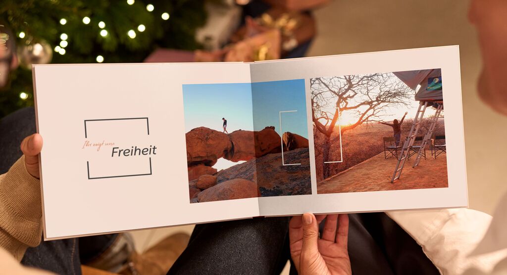 Zwei Seiten eines CEWE Fotobuchs mit dem Text „Freiheit“ und Bildern einer Person auf einem Felsen und einer sonnenunterganglichen Landschaft