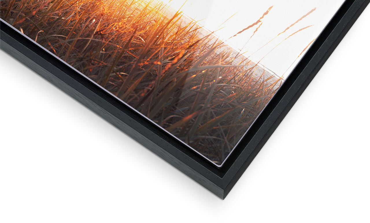 Nahaufnahme eines Rahmens mit einem bunten Bild von einem Sonnenuntergang über Gras.