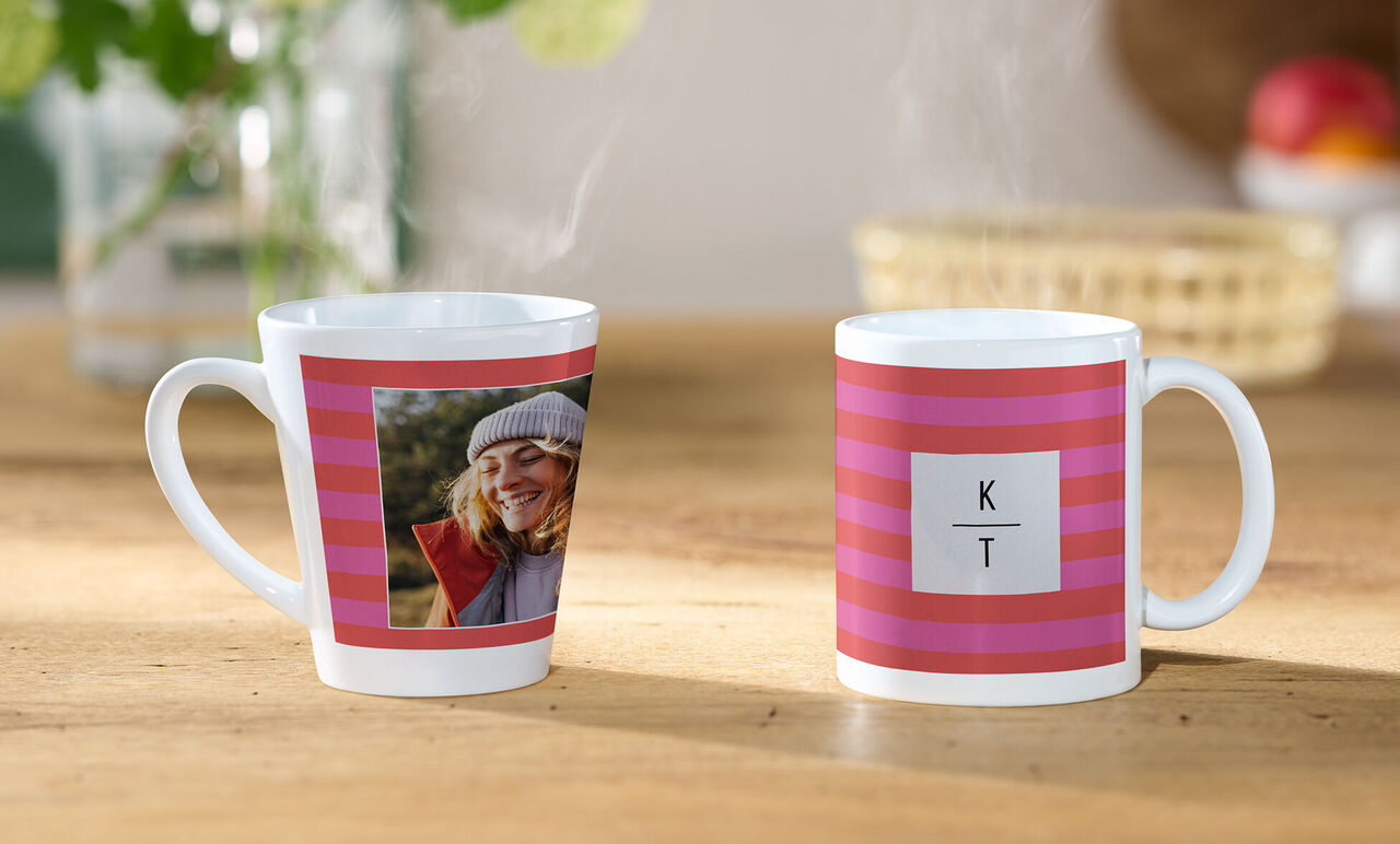 Zwei individuell gestaltete Tassen mit pink-rotem Streifenmuster, eine mit Foto und eine mit Initialen K und T