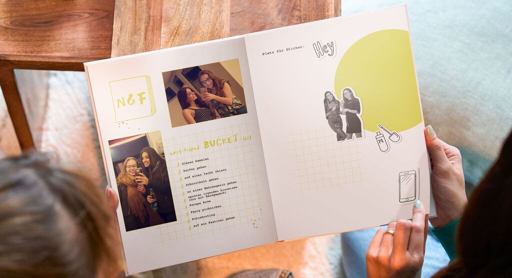 Zwei Personen zeigen ein kreativ gestaltetes Fotobuch mit Erinnerungen und Fotos