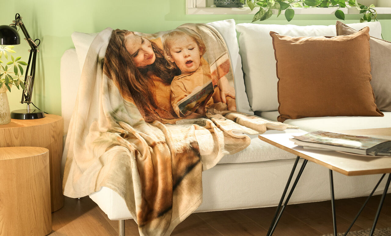 Wunderschöne Decke auf einem gemütlichen Sofa, umgeben von Pflanzen und einem Kissen