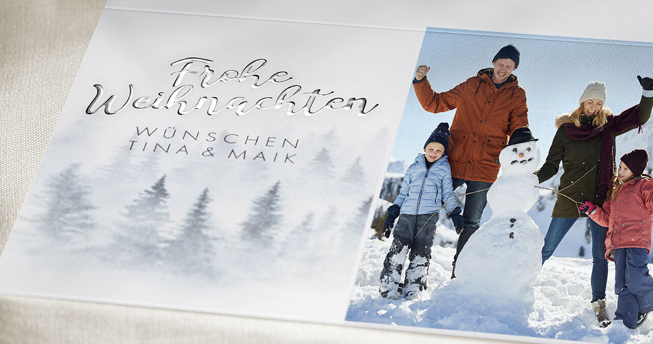 Familie feiert Weihnachten im Schnee mit Schneemann und festlichen Wünschen