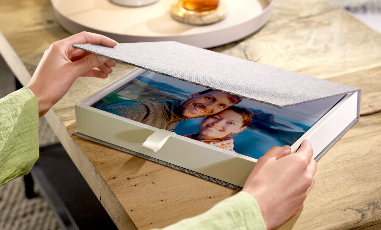 Person öffnet elegante Geschenkbox mit CEWE FOTOBUCH und Paarfoto", "title": "Geschenkbox mit CEWE FOTOBUCH