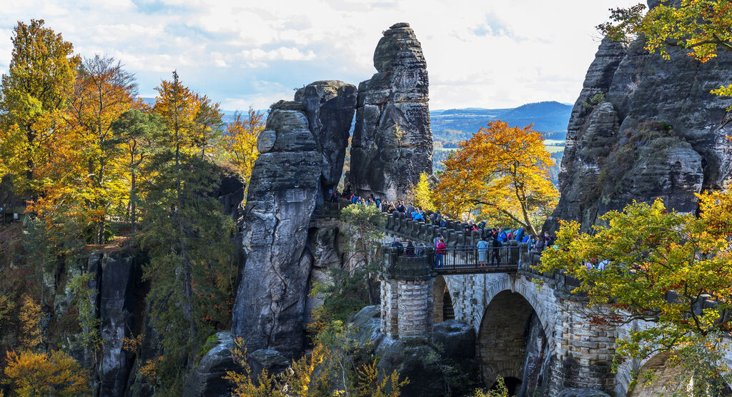 Die Basteibrücke in der Sächsischen Schweiz mit bunten Herbstbäumen und Menschen.
