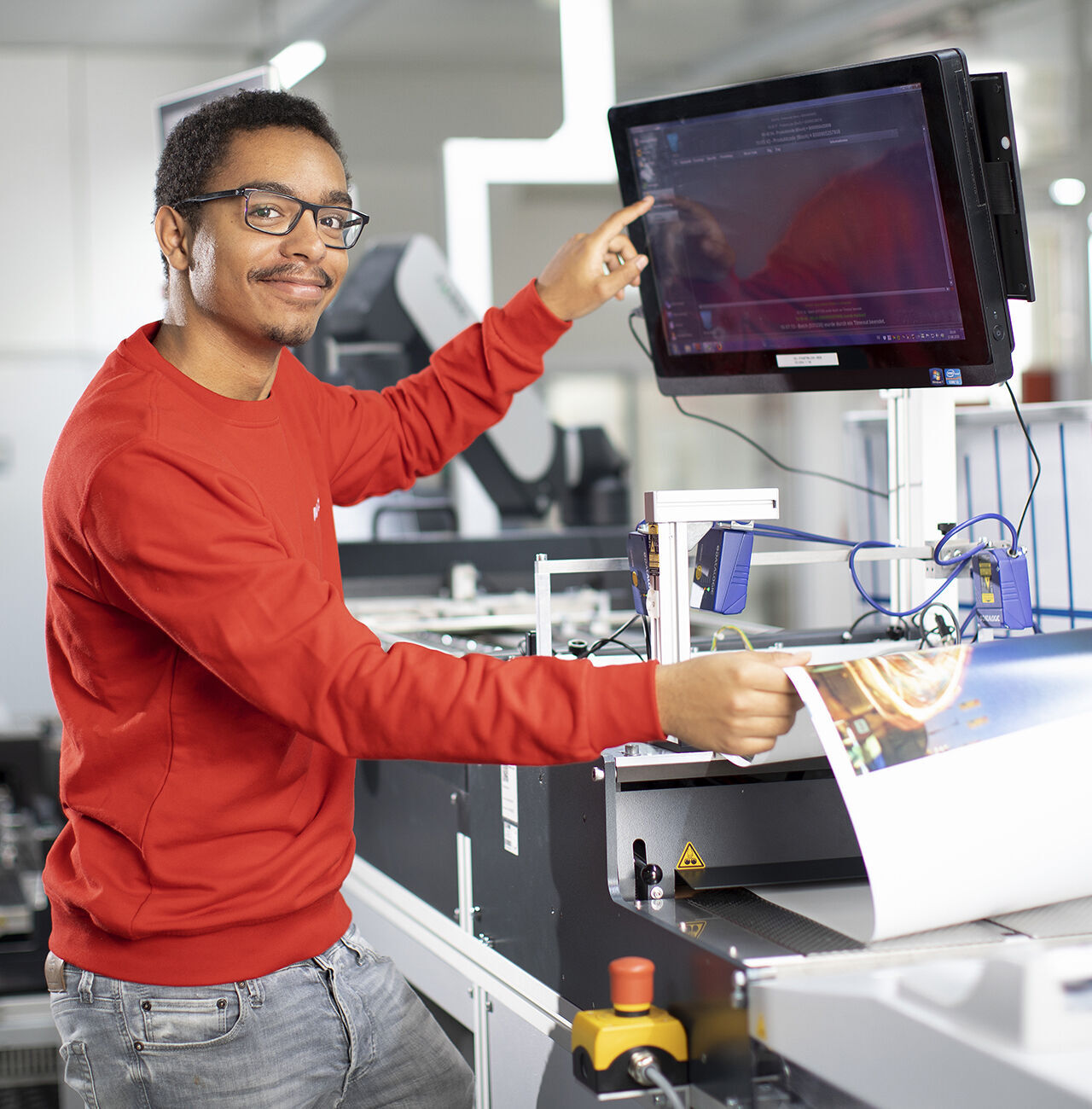 Ein Mitarbeiter zeigt auf einen Monitor in einer Produktionsumgebung